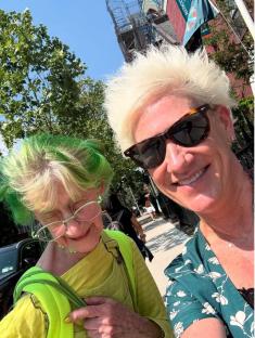 Photo of two women, one with bright green hair and the other with bleached blond hair, smiling for a selfie.