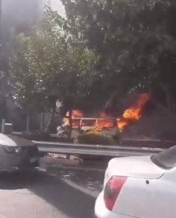 Van engulfed in flames on a road.