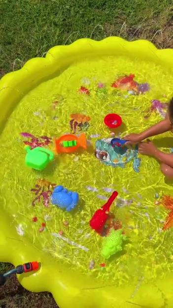 Child playing with toys in a yellow inflatable pool.