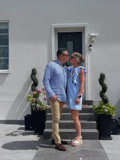 Couple kissing in front of their house.