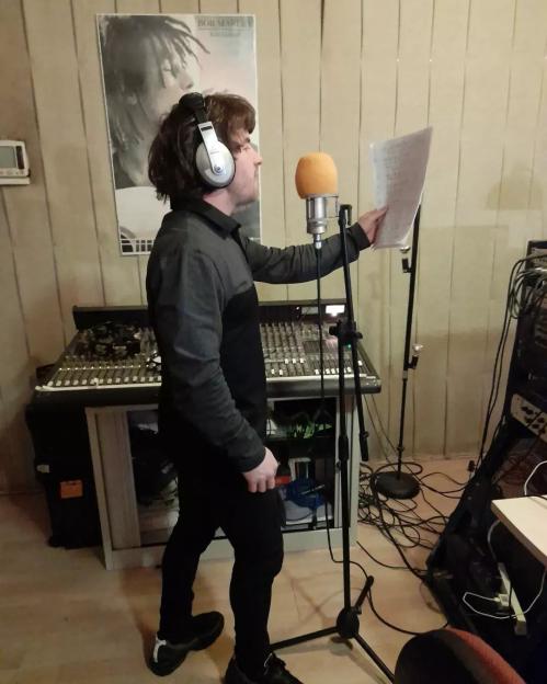 Anthony Russell singing into a microphone in a recording studio.