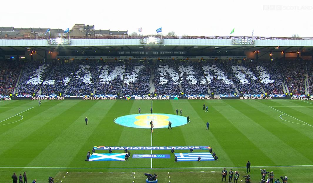 Players observing a moment of applause for Denis Law at Hampden Park.