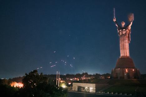Nighttime aerial view of missiles over Kyiv, Ukraine, with the Motherland Monument illuminated.