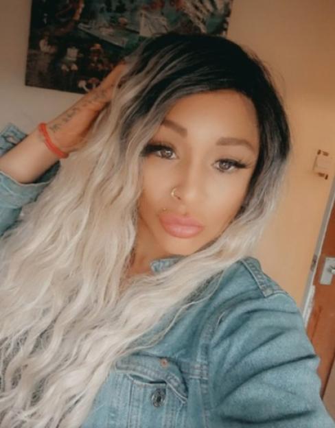 Woman with long blonde and black hair wearing a denim jacket.