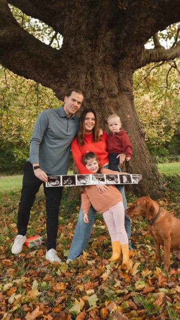 Family of four with dog announcing pregnancy with ultrasound images.
