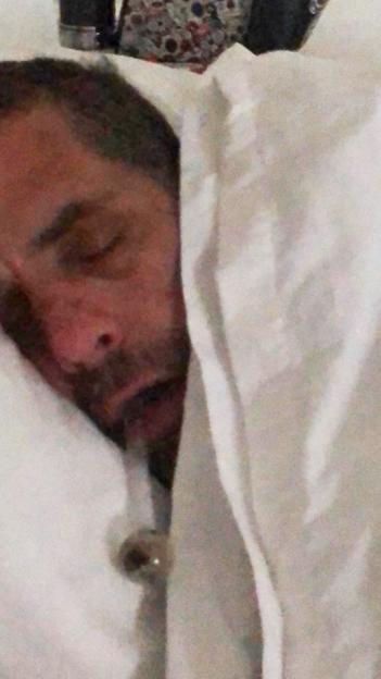 Man sleeping under white sheets.