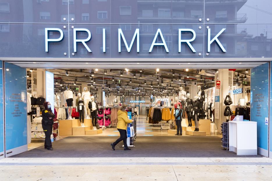 People wearing masks walk past a Primark store.