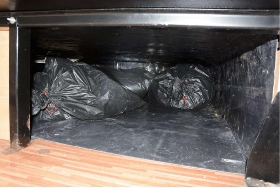 Large black trash bags in a motorhome's storage compartment.