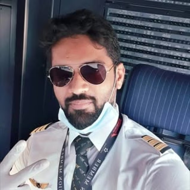 Portrait of a pilot wearing a facemask and sunglasses.