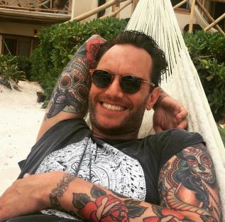 Man with tattoos relaxing in a hammock.