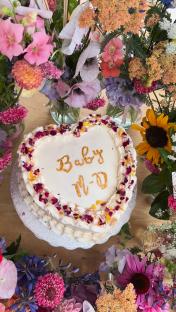 Heart-shaped baby shower cake decorated with flowers and the inscription