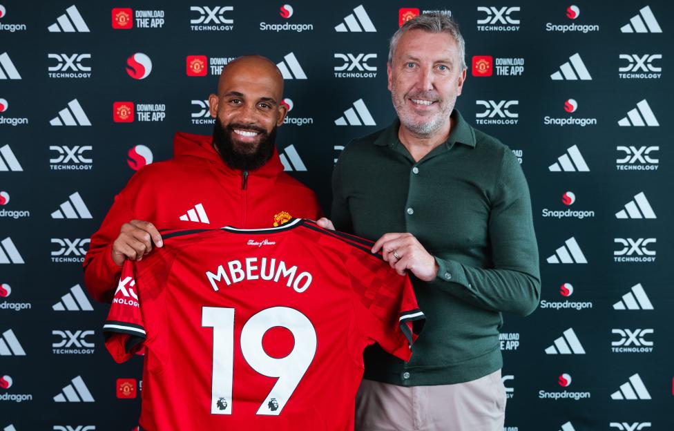 Bryan Mbeumo of Manchester United holding his new jersey with Director of Football Jason Wilcox.