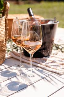 Two glasses of rosé wine on a white table outdoors.