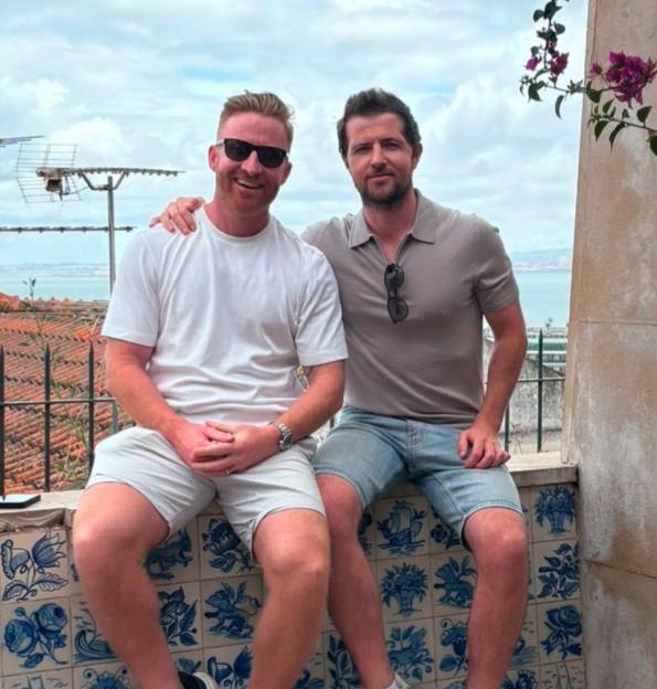 Two men sitting on a tiled wall, overlooking a cityscape.