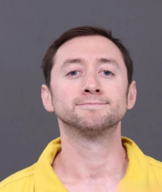 Mugshot of a man in a yellow shirt.