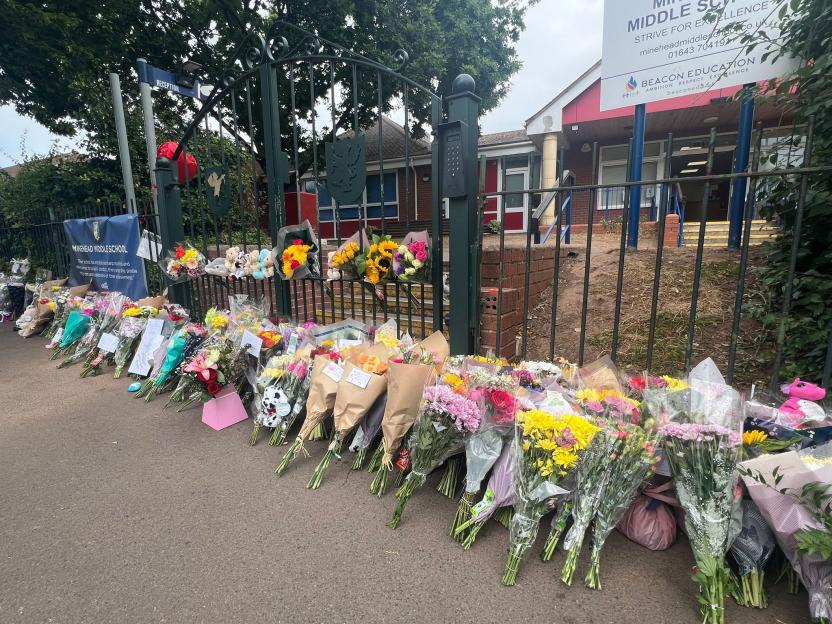 Floral tributes and stuffed animals left outside Minehead Middle School after a fatal bus crash.