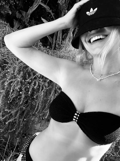 Black and white photo of a woman wearing a bikini and an Adidas bucket hat.