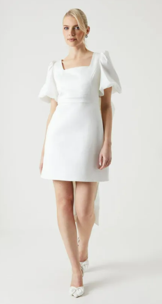 Woman in white mini dress with puff sleeves.