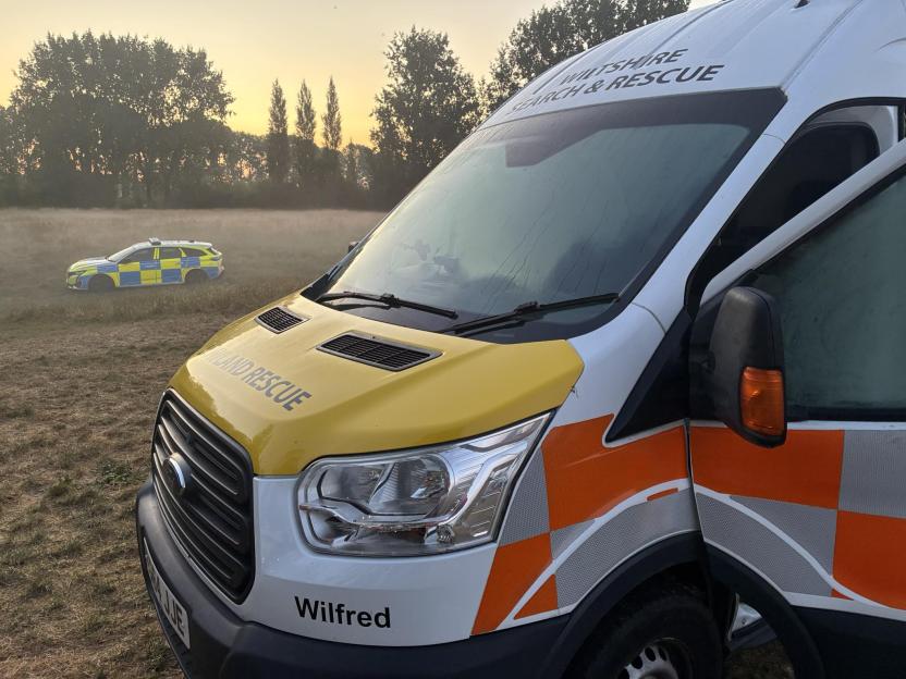 Search and rescue van and police car at a search site.