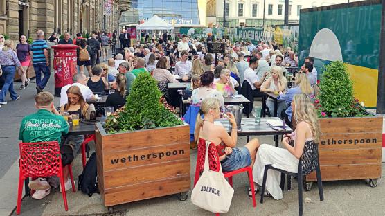 Patrons enjoying drinks at an outdoor Wetherspoon's pub in Glasgow.