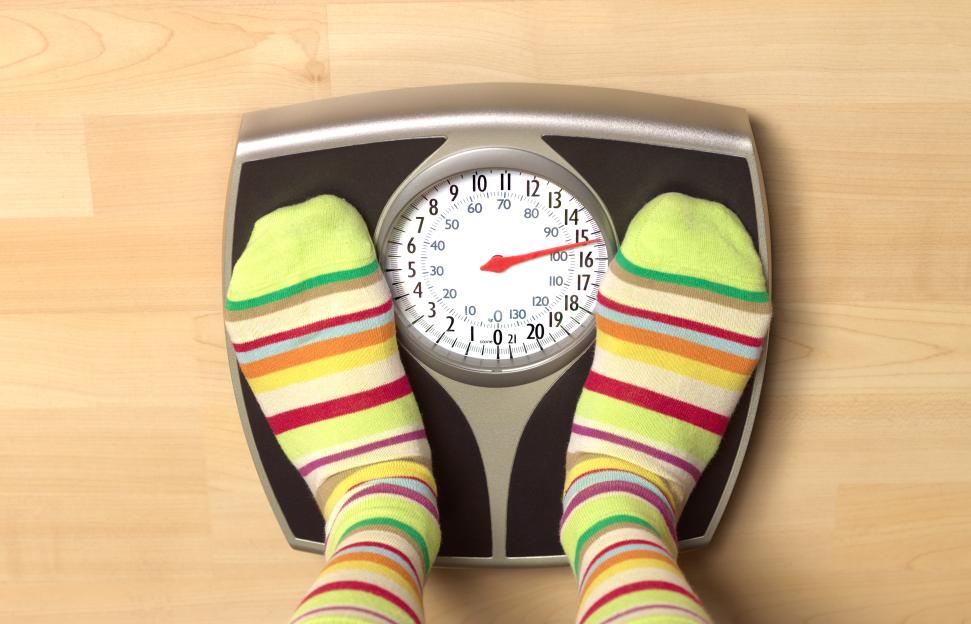 Feet in striped socks on a bathroom scale.