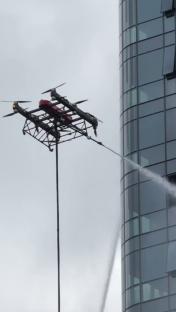 Tethered firefighting drone spraying water on a high-rise building.