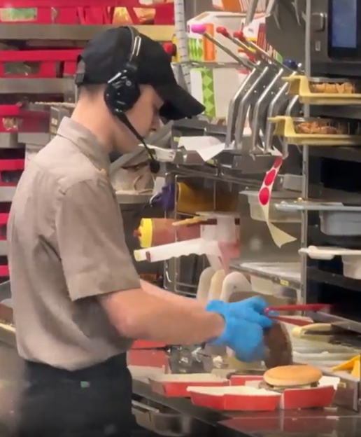 Fast food worker assembling a burger.