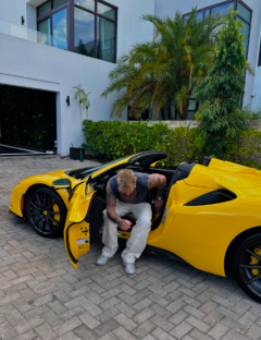 Man getting into a yellow convertible sports car.