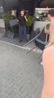 A man throwing chairs outside a restaurant.