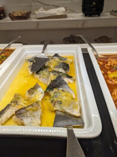 Fish in a yellow sauce in a buffet serving dish.