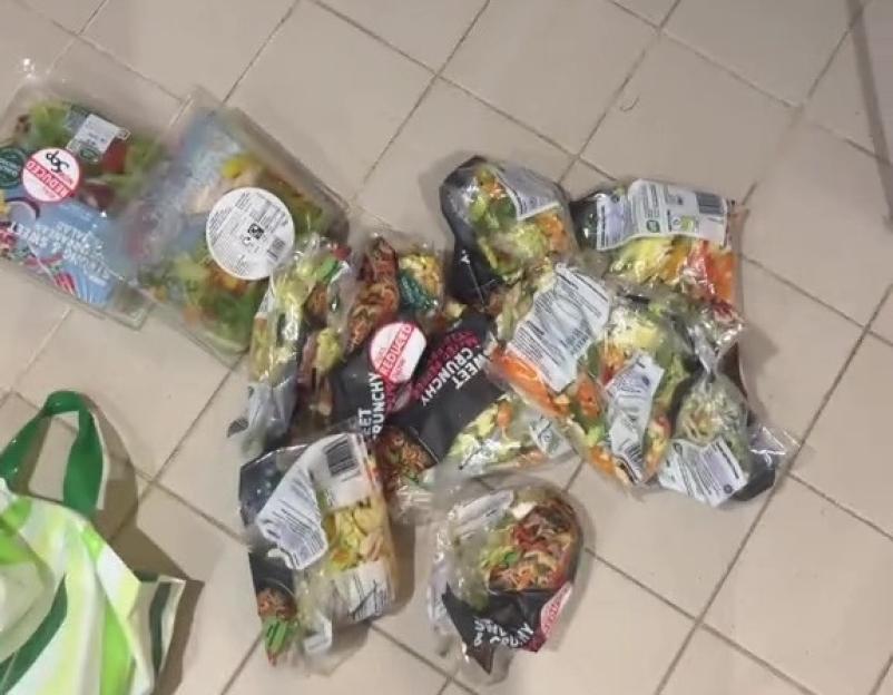 Pile of pre-packaged salad mixes on a tiled floor.