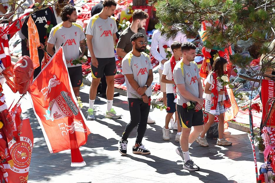 Liverpool players carrying flowers at a memorial for Diogo Jota.