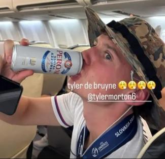 Man on airplane drinking Peroni beer.