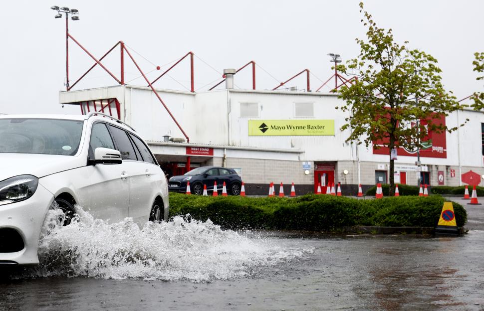Car splashing through a flooded stadium parking lot.