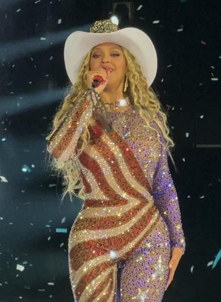Beyoncé performing in a sequined jumpsuit and cowboy hat.