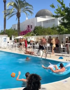 People swimming and playing in a pool at a resort.