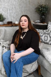 Woman sitting on a couch, looking at the camera.