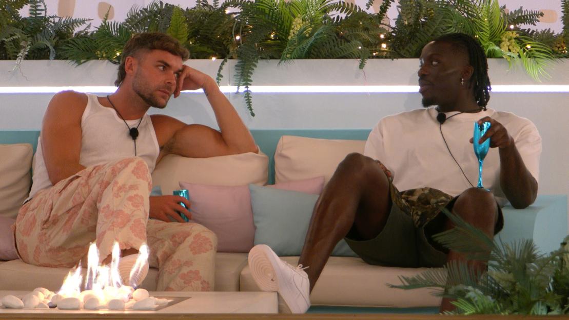 Two men sitting on a sofa, talking.