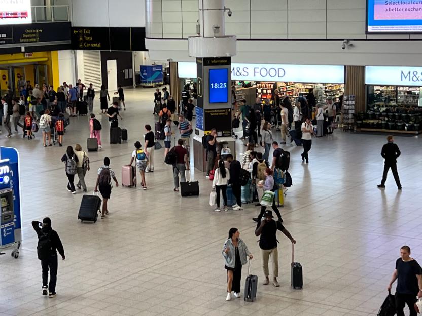 Airport terminal with many travelers and luggage.
