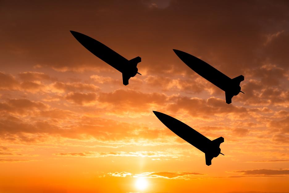Silhouette of three ballistic missiles flying at sunset.