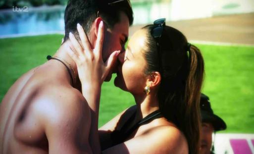 A couple kissing by a pool.