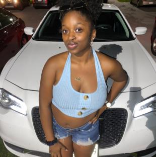 Photo of Sade Carleena Robinson in front of a car.