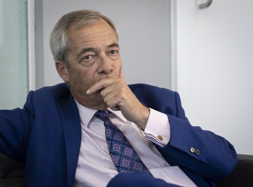 Nigel Farage in a blue suit, hand on chin.