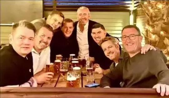 Group of men sitting together at a table, drinking beer.