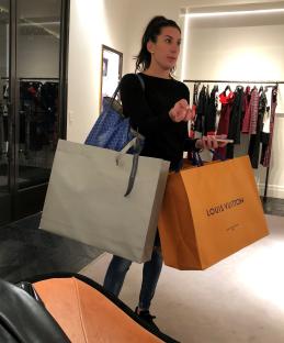 Woman carrying Louis Vuitton and Alexander McQueen shopping bags.