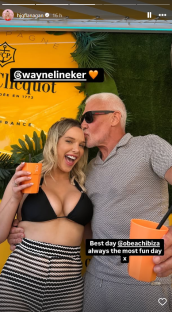 A man kissing a woman on the forehead; they are holding drinks.