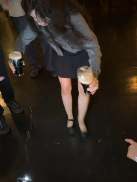 Woman juggling two pints of Guinness.