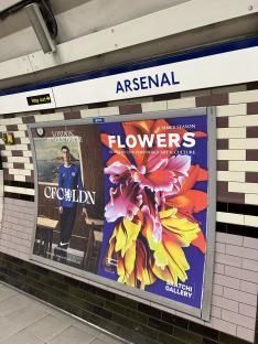 Arsenal station advertisements: Chelsea football kit and Saatchi Gallery flower exhibit.