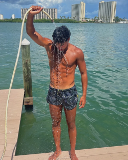 Man rinsing off with a hose on a dock.
