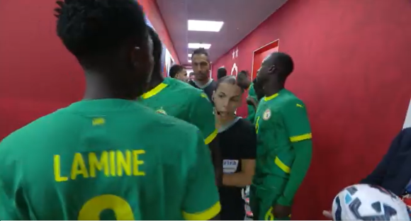 Soccer players in green jerseys walking down a hallway.
